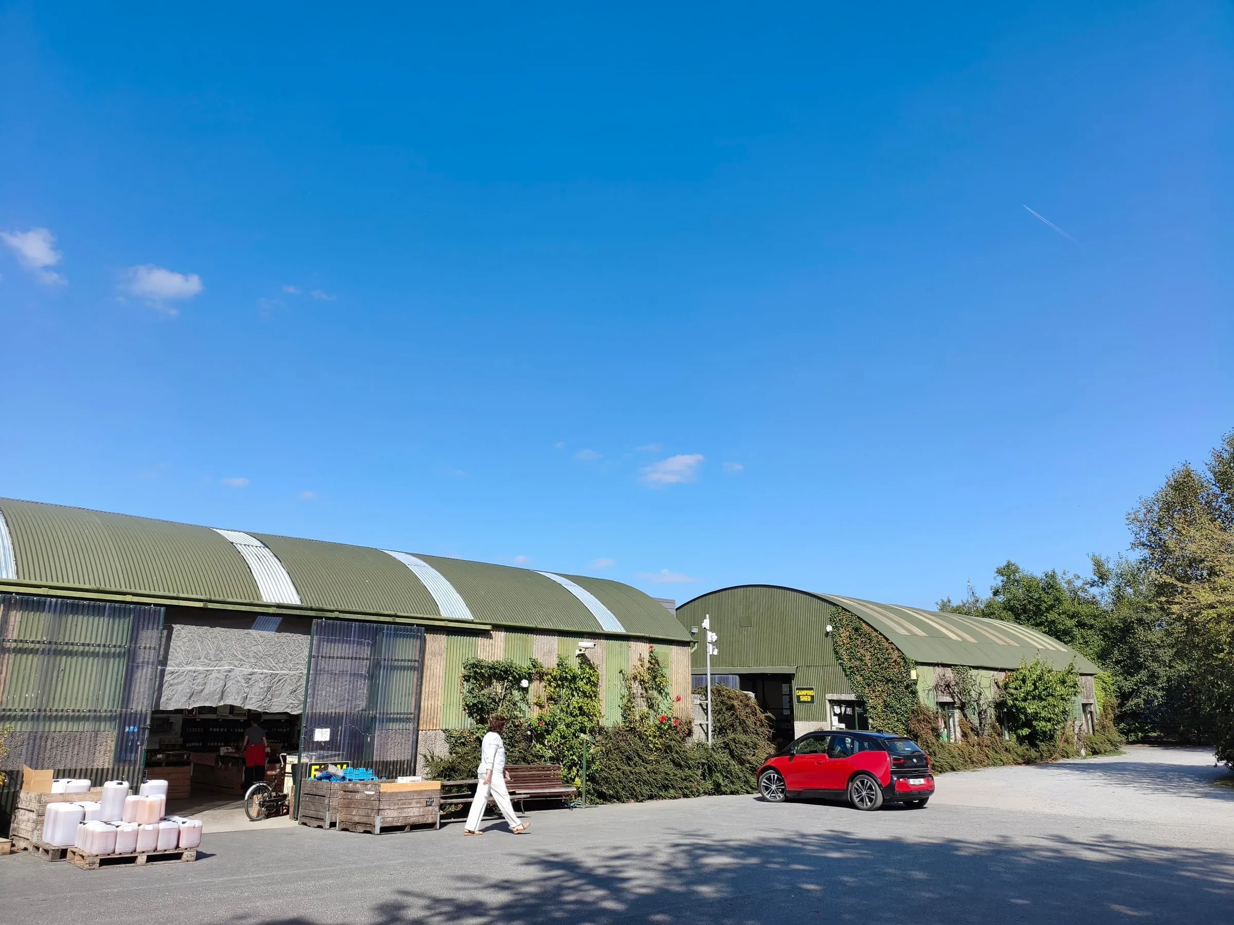 The farm shop barns at The Apple Farm on a sunny day, with crates of fruit outside the door